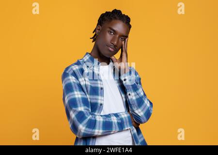 Pensive young black man touching face and looking at camer Stock Photo