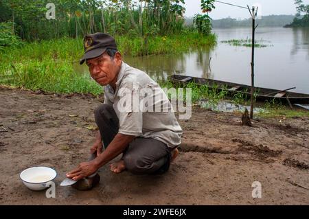 An inhabitant of the riverside village of Timicuro I sharpens a knife in front of his house. Iqutios peruvian amazon, Loreto, Peru. Stock Photo