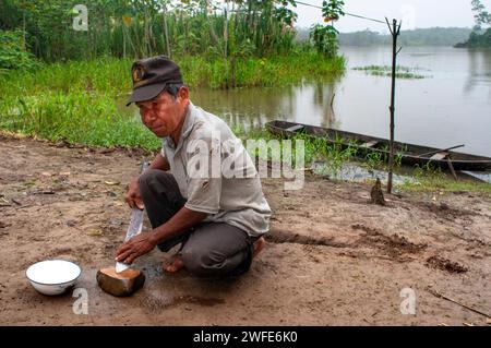 An inhabitant of the riverside village of Timicuro I sharpens a knife in front of his house. Iqutios peruvian amazon, Loreto, Peru. Stock Photo