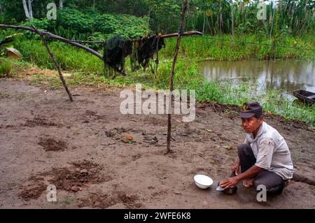 An inhabitant of the riverside village of Timicuro I sharpens a knife in front of his house. Iqutios peruvian amazon, Loreto, Peru. Stock Photo