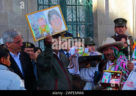 La Paz, BOLIVIA; 24th January 2015. Bolivian president Evo Morales holding up a picture of himself at an event to mark the start of the Alasitas festival in La Paz. The picture was a gift from the man on the right who is dressed as an Ekeko, an Aymara god of abundance associated with the festival. At the festival people buy miniatures of what they want to get during the year and have them blessed so their wishes come true. Popular miniatures available include cars, houses, money, degree certificates, suitcases and passports (for travel). Stock Photo