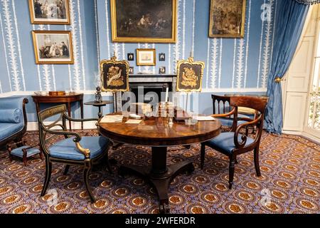 An 1830s drawing room with round table and armchairs Stock Photo