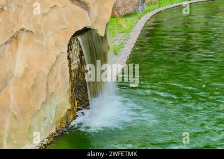 A small decorative waterfall in the garden. Landscape design. Small artificial waterfall in man made tropical garden Stock Photo