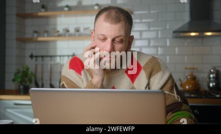 Cosy male sit in kitchen working from home with laptop. Male student thinking of inspiration search problem solution ideas lost in thoughts, dreaming Stock Photo