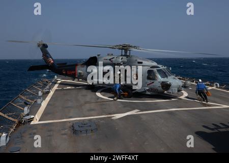 U.S. Navy Boatswain's Mate 3rd Class TyRhan Williams, left, and Gas Turbine Systems Technician (Mechanical) 3rd Class Jason Bird chock and chain a MH-60R helicopter attached to the “Swamp Foxes” of Helicopter Maritime Strike Squadron (HSM) 74 onto the flight deck of the guided-missile destroyer USS Laboon (DDG 58) in the Red Sea, Jan. 9, 2024. Laboon is deployed to the U.S. 5th Fleet Area of operations to help ensure maritime security in the Middle East region. (U.S. Navy photo by Mass Communication Specialist 3rd Class Alice Husted) Stock Photo