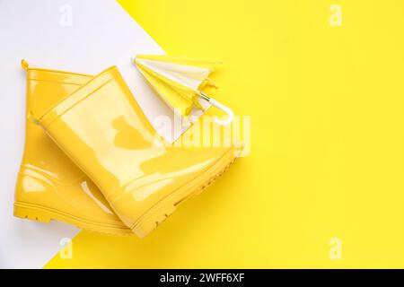 Mini stylish umbrella and gumboots on colorful background Stock Photo