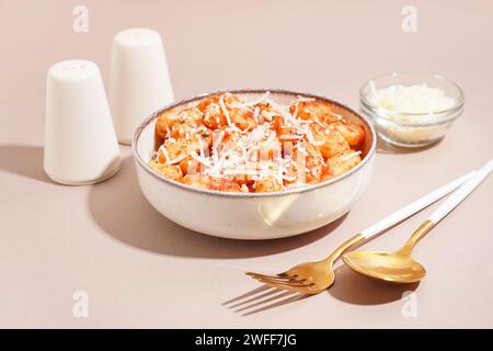 Bowl of tasty gnocchi with cheese on white background Stock Photo