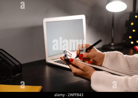 Woman with clipboard working in office at night, closeup Stock Photo