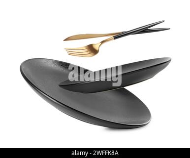 Clean plates, fork and knife falling on white background Stock Photo