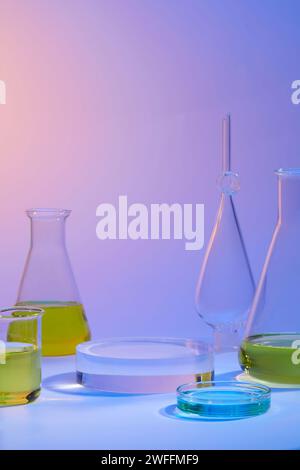 Petri dish of blue liquid and other glassware filled with yellow liquid. Decorated with round transparent podium Stock Photo