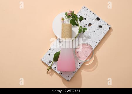 A stone podium with Lantana camara flowers, gradient jar and a glass petri dish filled with pink liquid placed on. Organic cosmetics packaging mockup Stock Photo