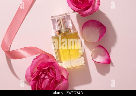 Glass transparent bottle of perfume displayed with Rose petals. Essential oil extracted from Rose (Rosa) can be used in perfume production. Empty labe Stock Photo