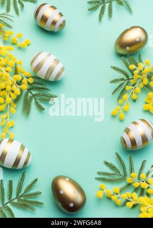 Mimosa branch, Easter eggs on light green background.  Beautiful Easter spring background with place for text. Stock Photo