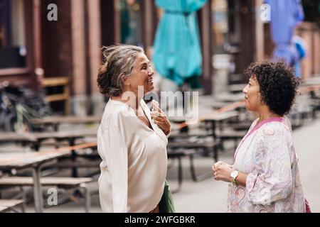 Smiling disabled woman talking with female friend while standing at street Stock Photo