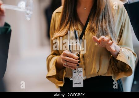Midsection of businesswoman holding champagne flute while gesturing during seminar Stock Photo