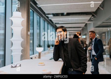 Smiling young businessman talking on mobile phone during conference Stock Photo