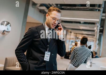 Young businessman talking on mobile phone during networking conference Stock Photo