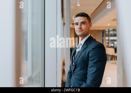 Portrait of confident businessman standing near window at office Stock Photo