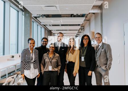 Portrait of smiling multiracial colleagues standing in corridor Stock Photo