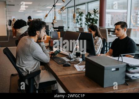 Multiracial colleagues sitting at desk working in corporate office Stock Photo