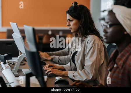 Young businesswoman using computer while sitting by female colleague at desk in office Stock Photo