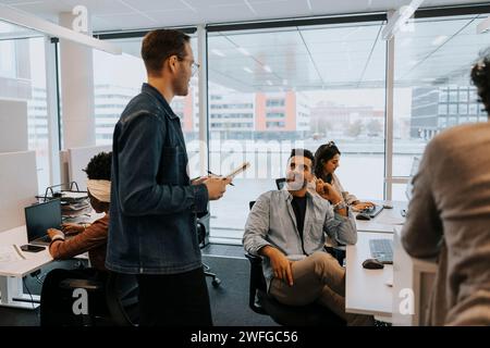 Businessmen discussing strategy amidst colleagues in office Stock Photo