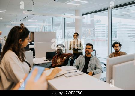 Multiracial colleagues listening to businesswoman discussing strategy at office Stock Photo