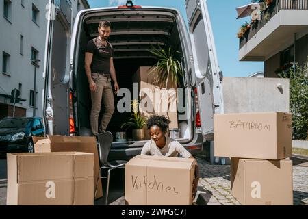 Smiling woman arranging boxes with boyfriend standing in van trunk Stock Photo