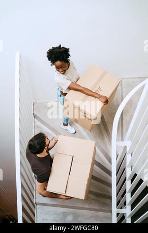 High angle view of multiracial couple carrying boxes while moving up on staircase at home Stock Photo