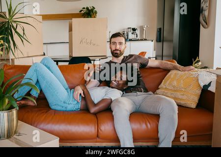 Portrait of multiracial couple relaxing on sofa in living room at new home Stock Photo