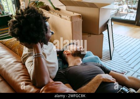 Multiracial couple relaxing together on sofa in living room at new home Stock Photo