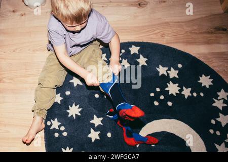High angle view of boy wearing socks while sitting on carpet at home Stock Photo