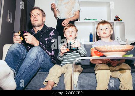 Father playing video game with son while sitting on sofa at home Stock Photo