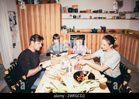 Family having dinner while sitting at dining table in kitchen Stock Photo