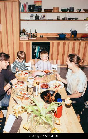 High angle view of happy family having fun while having dinner at dining table in kitchen Stock Photo