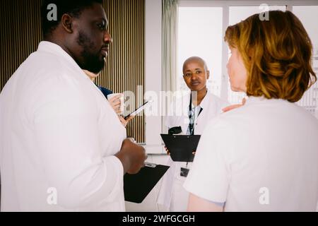 Team of multiracial medical discussing while standing at hospital Stock Photo