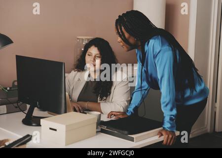 Multiracial female business colleagues discussing over computer at desk in office Stock Photo