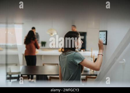 Girl using digital tablet mounted on wall by family at modern home Stock Photo