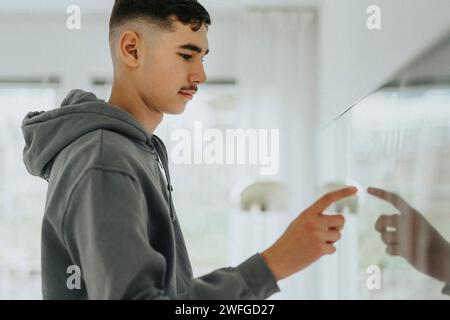 Side view of teenage boy touching smart TV screen in living room at home Stock Photo