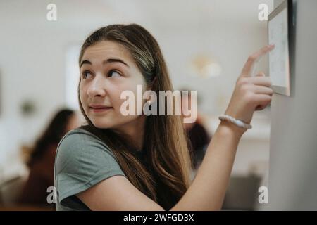 Pre-Adolescent girl adjusting room temperature over digital tablet at smart home Stock Photo