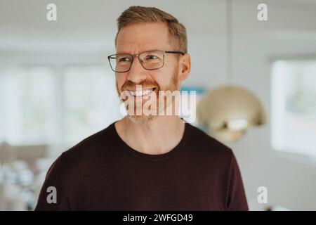 Smiling mature man wearing eyeglasses looking away at modern home Stock Photo