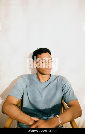 Young man with eyes closed sitting on chair under sunlight at backyard Stock Photo