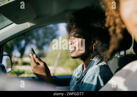 Smiling young woman using smart phone in car Stock Photo