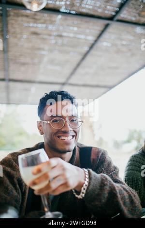 Portrait of smiling young man sitting with drink at patio during dinner party Stock Photo