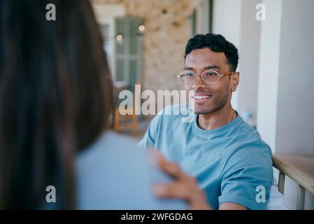 Smiling young man talking with woman sitting in patio Stock Photo