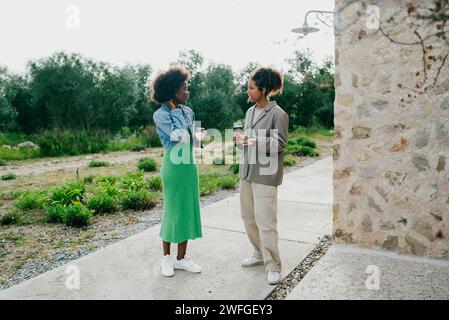 Full length of young woman talking with female friend in backyard Stock Photo