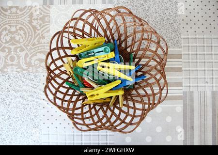 Multicolored clothespins in the wicker basket, top view Stock Photo