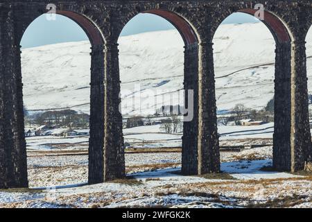 The Ribblehead Viaduct in winter in the Yorkshire Dales, with lots of snow on the ground and dramatic mountain scenery. Taken on a sunny day. Stock Photo