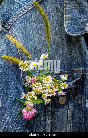 Bouquet of wildflowers in the pocket of a denim jacket Stock Photo