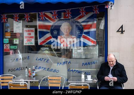 9th September 2022: The day after the official announcement of the death of Her Majesty Queen Elizabeth II a man sits outside a cafe in Westminster London which is bedecked in royal memorabilia. The Queen died at Balmoral Castle in Scotland at the age of ninety-six. Her reign was the longest of any British monarch. Stock Photo